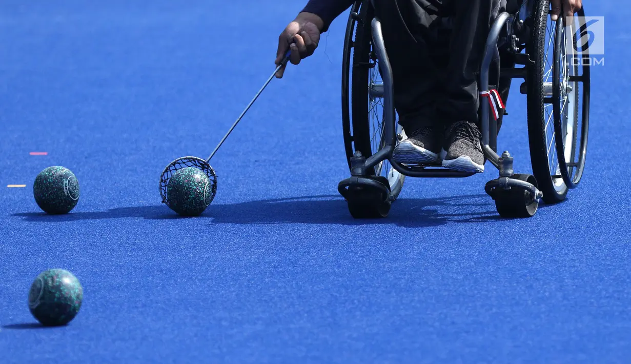 Atlet Para Games Indonesia cabang olahraga Lawn Bowls mengambil bola saat latihan di Lapangan Hoki Kompleks GBK, Jakarta, Selasa (18/9). Latihan ini adaptasi lapangan sekaligus persiapan jelang Asian Para Games 2018. (Liputan6.com/Helmi Fithriansyah)