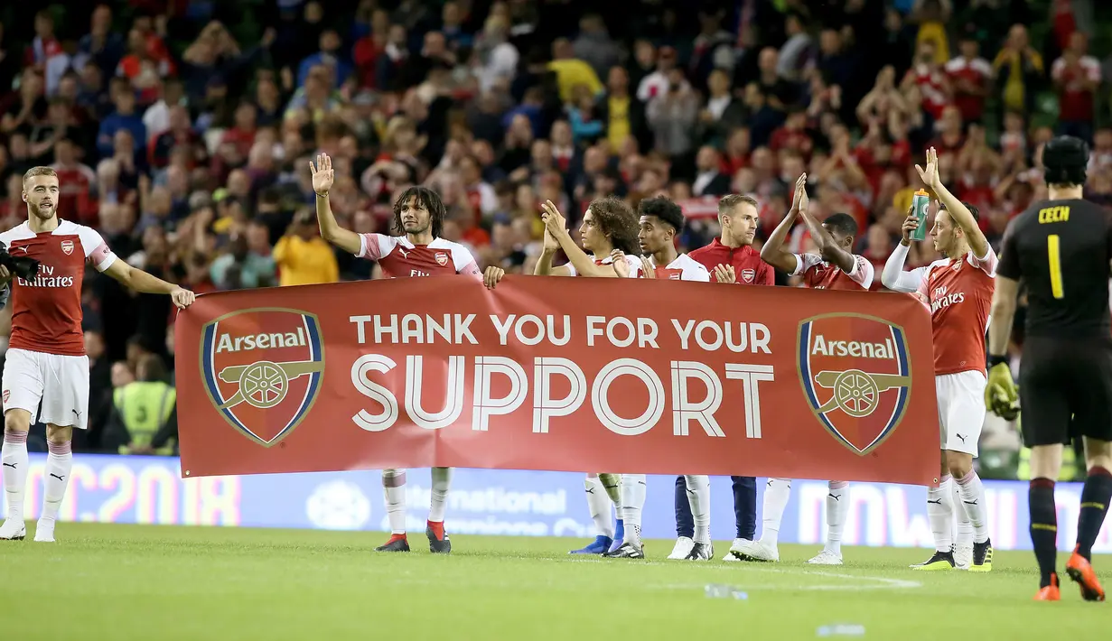 Para pemain Arsenal membawa spanduk menyapa suporter usai pertandingan melawan Chelsea pada  International Champions Cup (ICC) di Stadion Aviva di Dublin (1/8). Arsenal menang atas Chelsea lewat adu penalti 6-5. (AFP Photo/Paul Faith)