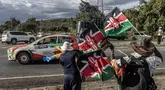 Pembalap Italia, Riccardo Garosci memacu mobilnya, Mitsubishi Lancer Evo X bersama co-driver Rudy Briani melewati pedagang bendera Kenya dan vuvuzelas saat Safari Relly Kenya di Naivasha, Kenya, 28 Maret 2024. (AFP/Luis Tato)