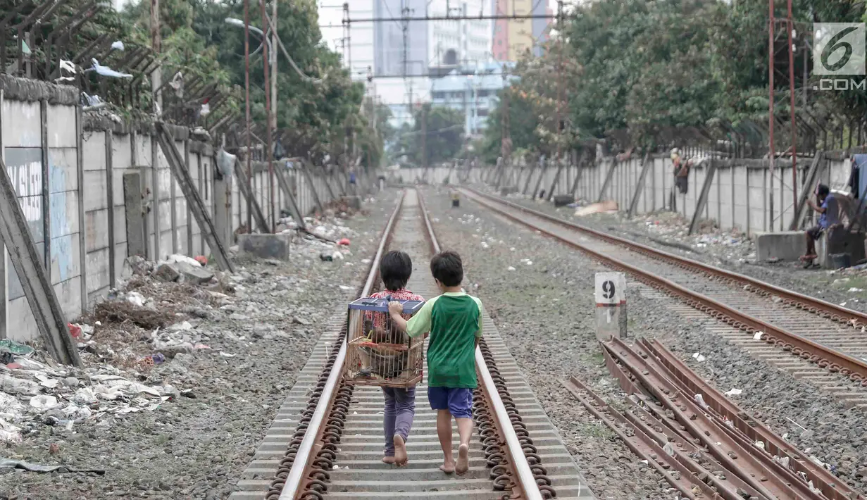 Dua anak berjalan usai bermain di sekitar rel kereta api di kawasan Pademangan, Jakarta, Kamis (8/11). Kurangnya lahan bermain menyebabkan anak-anak tersebut bermain di tempat yang tidak semestinya dan membahayakan. (Liputan6.com/Immanuel Antonius)