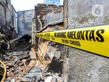 Garis polisi terpasang saat seorang petugas pemadam kebakaran melakukan pemadaman pada bangunan pascakebakaran yang melanda kawasan permukiman padat penduduk di Petojo Selatan, Jakarta, Kamis (24/8/2023). Kebakaran tersebut menghanguskan bangunan yang dihuni 196 kepala keluarga (KK) dan merenggut korban jiwa dua orang lansia. (Liputan6.com/Johan Tallo)