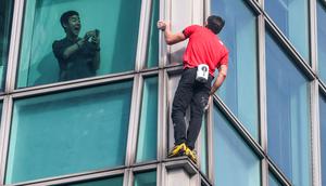 Seorang penghuni gedung merekam aksi atlet panjat tebing 'free solo' asal Amerika, Alex Honnold saat memanjat gedung Taipei 101 tanpa tali pengaman di Taipei, Minggu (25/01/2026). (AFP/I-Hwa Cheng)