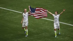 Bek AS, Becky Sauerbrunn (kiri) dan bek Meghan Klingenberg mengibarkan bendera merayakan gelar juara Piala Dunia wanita 2015 di BC Place, Kanada, Senin (6/7/2015). Amerika berhasil mengalahkan Jepang dengan skor 5-2.  (Reuters/Anne Marie Sorvin)