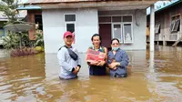 Warga Berau di depan rumahnya yang terendam banjir. (foto: Zuhri)