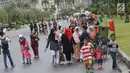 Warga bersama anak-anak berjalan-jalan di kawasan Monumen Nasional, Jakarta, Jumat (19/4). Libur panjang perayaan Paskah 2019 dimanfaatkan warga untuk berwisata di kawasan Monumen Nasional. (Liputan6.com/Helmi Fithriansyah)