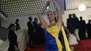 Seorang pengunjuk rasa yang mengenakan gaun berwarna bendera Ukraina melakukan demonstrasi dramatis di karpet merah Festival Film Cannes. (AP Photo/Daniel Cole)
