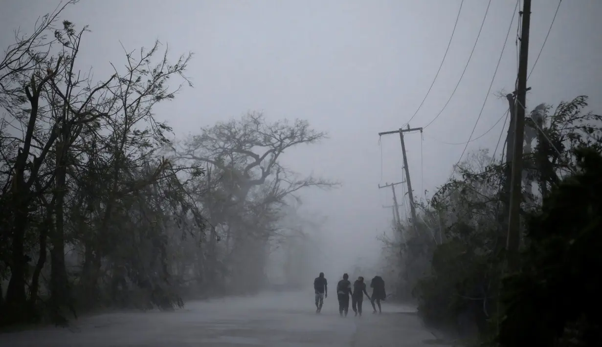 Warga berjalan di bawah tiang listrik setelah Badai Matthew menghantam wilayah Les Cayes di Haiti (4/10). Badai Matthew ini telah mengakibatkan banjir, banyak pohon tumbang dan ratusan rumah warga rusak parah. (REUTERS/Andres Martinez Casares)