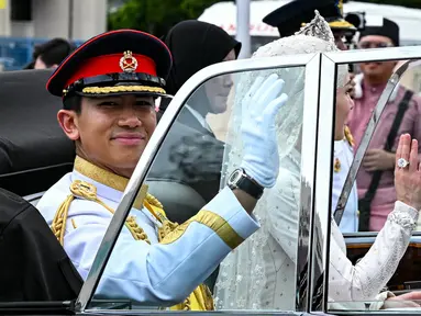 Pangeran Abdul Mateen dan Yang Mulia Anisha Rosnah melambaikan tangan dari mobil mereka saat prosesi pernikahan di ibu kota Brunei Darussalam, Bandar Seri Begawan, 14 Januari 2024. (MOHD RASFAN/AFP)