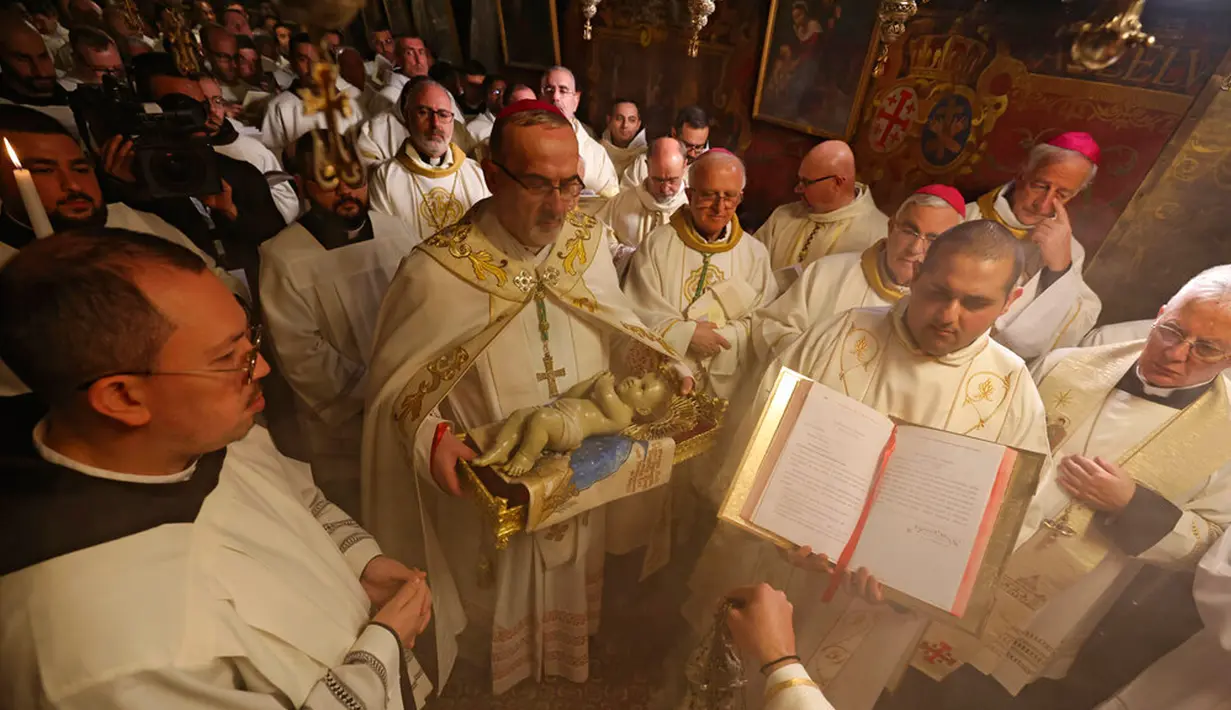 <p>Patriark Latin Yerusalem, Pierbattista Pizzaballa memimpin Misa Malam Natal di Kompleks Gereja Kelahiran Yesus, Bethlehem, Tepi Barat, Minggu (25/12/2022). Setelah dua tahun tutup karena COVID-19, jemaat kembali menghadiri ibadah tersebut kendati jumlahnya tidak sebanyak sebelum pandemi. (Ahmad Gharabli/Pool Photo via AP)</p>