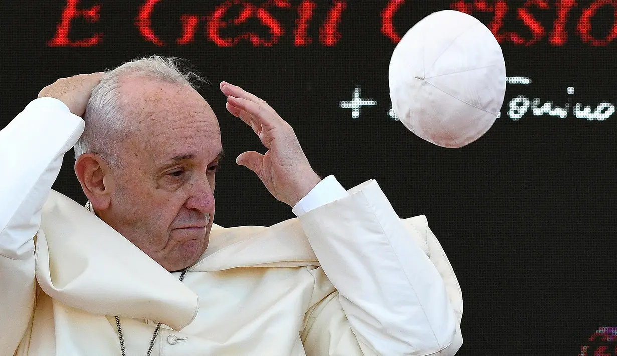 Paus Fransiskus memegang kepala saat menghadiri upacara peringatan 25 tahun kematian Don Tonino Bello di Alessano, Italia (20/4). Angin yang tiba-tiba bertiup membuat zucchetto yang dipakai Paus Fransiskus terbang dari kepalanya. (AFP/Vincenzo Pinto)