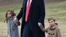 Donald Trump berjalan bersama cucunya, Arabella dan Joseph Kushner saat berangkat dari Gedung Putih, di Washington, AS, (17/2). Arabella dan Joseph merupakan anak dari putri sulung Trump, Ivanka Trump dan Jared Kushner. (AFP Photo/ Mandel Ngan)