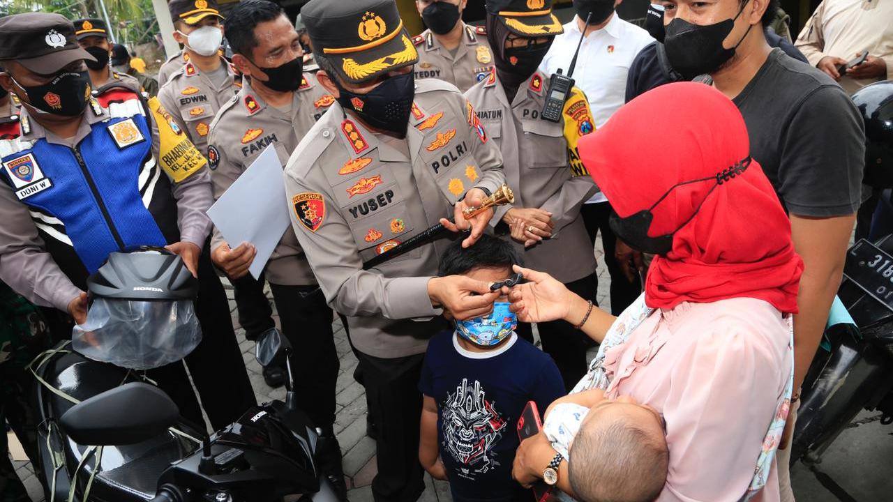 Kapolrestabes Surabaya Kombes Pol Akhmad Yusep Gunawan menyerahkan motor dari Jokowi untuk  Wahyu Novi Arini. (Dian Kurniawan/Liputan6.com)