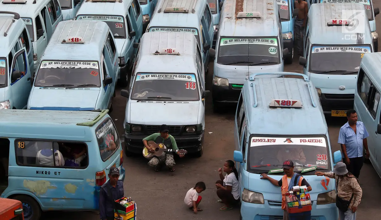 Pedagang menungu calon pembeli diantara deretan angkot di Terminal Kampung Melayu, Jakarta, Rabu (12/7). Angkot ber-AC ini merupakan bagian dari upaya untuk meningkatkan pelayanan angkutan umum kepada masyarakat. (Liputan6.com/Immanuel Antonius)