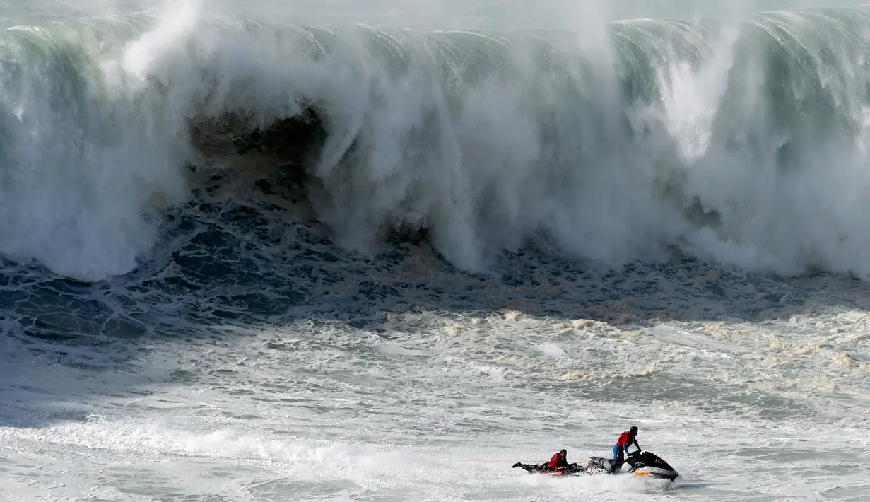 Peselancar ditarik menggunakan jet ski setelah jatuh ketika unjuk kebolehan dalam menaklukkan ombak besar di Praia do Norte atau Pantai Utara, Nazare, Portugal, Rabu (20/11/2019). Hanya peselancar profesional yang boleh bermain ombak di perairan ini. (AP Photo/Armando Franca)