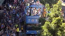 Pemain Manchester City melambaikan tangan dari atas bus beratap terbuka saat parade merayakan keberhasilan menjadi juara Liga Primer Inggris di Manchester, Senin (14/5). Sekitar 100 ribu fans ManCity membirukan Kota Manchester. (Danny Lawson/PA via AP)