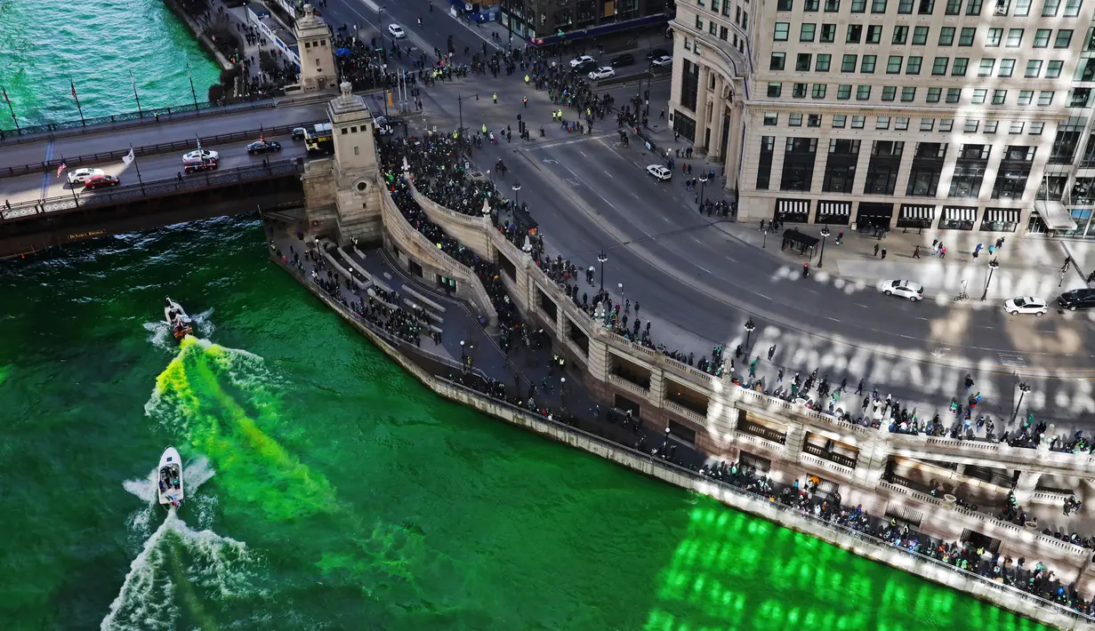 Wisatawan berkumpul mengamati sungai Chicago di Illinois, AS yang berubah warna menjadi hijau, 11 Maret 2017. Hijaunya warna sungai itu sebenarnya berasal dari cairan pewarna khusus untuk perayaan St. Patrick's Day. (John J. Kim/Chicago Tribune via AP)