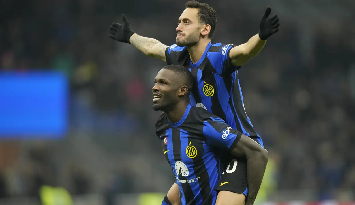 Gelandang Inter Milan Hakan Calhanoglu (atas) berselebrasi bersama Marcus Thuram setelah mencetak gol kedua timnya ke gawang Frosinone dalam duel pekan ke-12 Serie A 2023/2024 di Giuseppe Meazza, Senin (13/11/2023) dini hari WIB. (AP Photo/Luca Bruno)