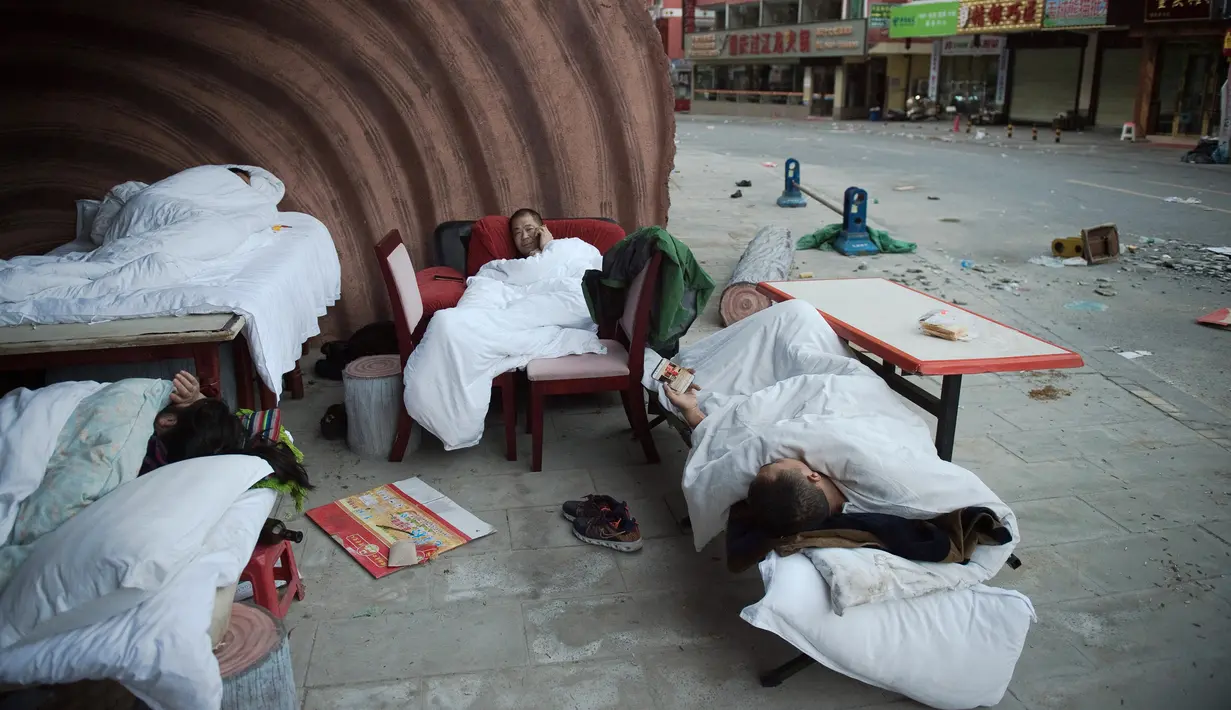 Sejumlah orang tidur di luar rumah mereka di Zhangzha, provinsi Sichuan, China barat daya, Kamis (10/8). Ratusan warga memilih menghabiskan malam di luar rumah setelah gempa 6,5 SR mengguncang wilayah itu dan menewaskan belasan orang (Nicolas ASFOURI/AFP)