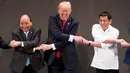 Ekspresi Presiden AS, Donald Trump saat bersalaman khas ASEAN dengan para pemimpin lainnya di penghujung upacara pembukaan KTT ASEAN di Manila, Filipina, Senin (13/11). Trump kesulitan menempatkan tangannya di posisi yang pas. (AP/Andrew Harnik)
