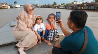 Mahmuda (kiri) bersama keluarga menikmati wisata Susur Sungai Martapura dua hari setelah lebaran menuju Kampung Hijau, Kota Banjarmasin Kalimantan Selatan, Minggu (23/4/2023). Liputan6.com/Aslam Mahfuz