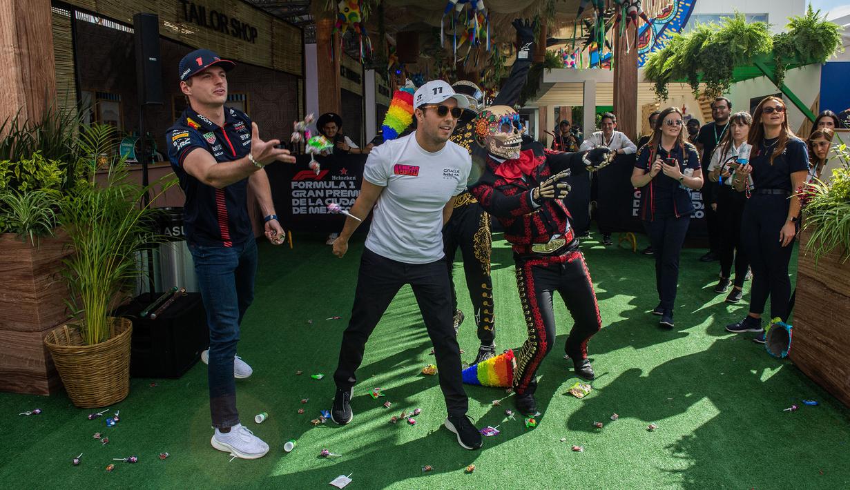 Pembalap Red Bull Racing, Sergio Perez (tengah) dan Max Verstappen membagikan permen setelah memecahkan pinata pada rangkaian acara menjelang Formula 1 GP Meksiko 2023 di paddock Sirkuit Hermanos Rodriguez, Meksiko, Kamis (26/10/2023) waktu setempat. (AFP/Claudio Cruz)