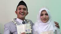 Komedian Caisar Aditya Putra dan Intan Sri Mardiani menunjukkan buku nikah usai melangsungkan ijab kabul pernikahan di kawasan Cimahpar, Bogor, Jawa Barat, Sabtu (30/6). (Liputan6.com/Herman Zakharia)