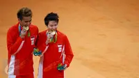 Pasangan ganda campuran Indonesia, Tontowi Ahmad dan Liliyana Natsir mengigit medali emas usai mengalahkan lawannya asal Malaysia Peng Soon Chan dan Liu Ying Goh pada final bulutangkis di Riocentro Pavilion 4 , Brasil. (REUTERS/Mike Blake)