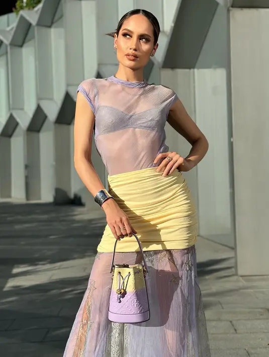 OOTD penuh warna ala Cinta Laura saat berlibur keluar negeri. Dengan atasan bralette dilapisi kaus lengan pendek transparan bernuansa ungu muda, Cinta Laura tampil kece dipadu dengan rok kerut berwarna kuning, disambung kain panjang transparan bermotif dengan warna ungu senada. Foto: Instagram.