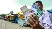 Warga menunjukkan uang pecahan Rupiah di layanan penukaran uang receh di Monas, Jakarta, Selasa (30/6). Bank Indonesia bekerjasama dengan 14 bank lainnya membuka loket penukaran uang pecahan kecil sejak 17 Juni-15 Juli 2015. (Liputan6.com/Faizal Fanani)