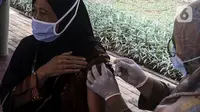 Tenaga kesehatan menyuntikkan vaksin booster kepada warga di sentra vaksinasi jemput bola RPTRA Taman Jangkrik, Ciganjur, Jakarta Selatan, Selasa (19/7/2022). Kementerian Kesehatan mencatat capaian vaksinasi booster COVID-19 secara nasional masih di angka 25,48 persen atau sebanyak 53.056.762 orang dari target penerima 208 juta orang. (Liputan6.com/Johan Tallo)
