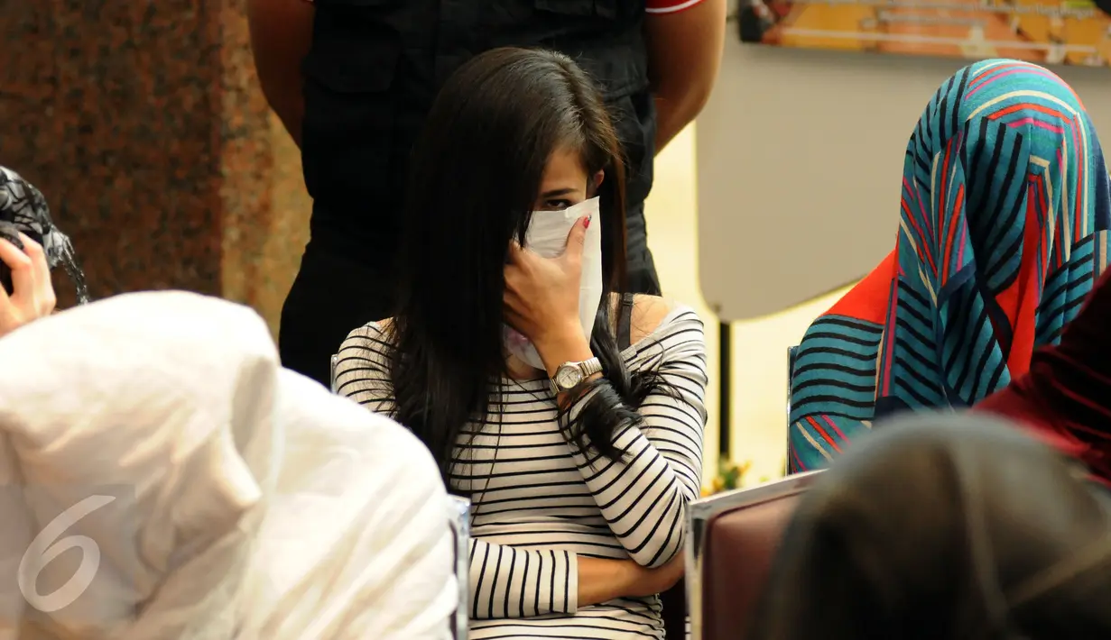 Salah satu warga negara asing illegal yang terjaring operasi pengawasan menutupi wajah saat rilis di Ditjen Imigrasi, Jakarta, Jumat (13/1). Diduga, para WNA tersebut bekerja sebagai pekerja seks komersial (PSK). (Liputan6.com/Helmi Fithriansyah)