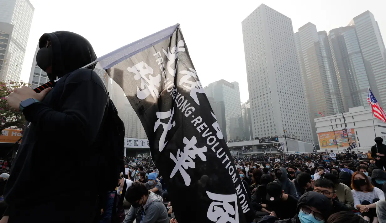 Seorang pria memegang bendera unjuk rasa untuk menunjukkan dukungan untuk Uighur dan perjuangan mereka terhadap hak azasi manusia di Hong Kong, Minggu (22/12/2019). Demonstran memprotes kebijakan China terkait minoritas Uighur. (AP Photo/Lee Jin-man)