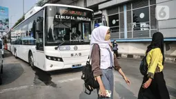 Pejalan kaki melintas di depan bus listrik Transjakarta rute Kampung Melayu-Tanah Abang via Cikini (5M) saat uji coba di Terminal Kampung Melayu, Jakarta Timur, Selasa (26/7/2022). PT Transjakarta mengubah rute uji coba bus listrik yang sebelumnya jurusan Kampung Melayu-Tanah Abang (5F) agar masyarakat dapat menjajal secara merata sekaligus memperkenalkan jalur bus yang melayani mulai pukul 05.00-21.00 WIB. (merdeka.com/Iqbal S Nugroho)