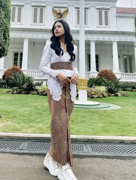 Maudy Ayunda tampil dengan kebaya putih dipadukan obi dan kain batik coklat serasi, ia juga mengenakan sneakers putih. [Instagram/@maudyayunda]