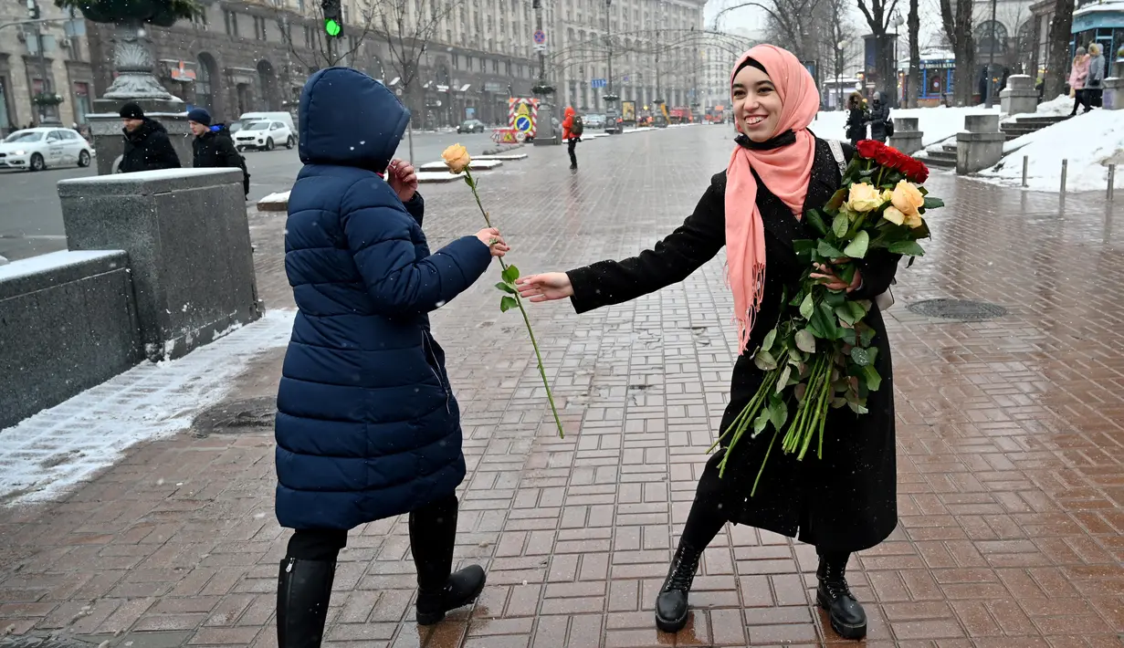 Seorang aktivis dari Asosiasi Perempuan Muslim Ukraina memberikan bunga kepada pejalan kaki selama perayaan World Hijab Day di Kiev, Senin (1/2/2021). Hari Hijab Sedunia untuk menunjukkan solidaritas dengan wanita Muslim yang mengalami diskriminasi untuk mengenakan hijab. (Sergei SUPINSKY/AFP)