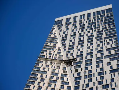 Puing-puing bergelantungan terlihat dari gedung apartemen yang rusak di jalan Mosfilmovskaya, Moskow, setelah serangan pesawat tak berawak dari Ukraina, Senin 4 Mei 2026. ebuah pesawat tak berawak (drone) dari Ukraina menghantam sebuah gedung pencakar langit yang menjadi kompleks hunian warga di Moskow, Rusia. (AP Photo)
