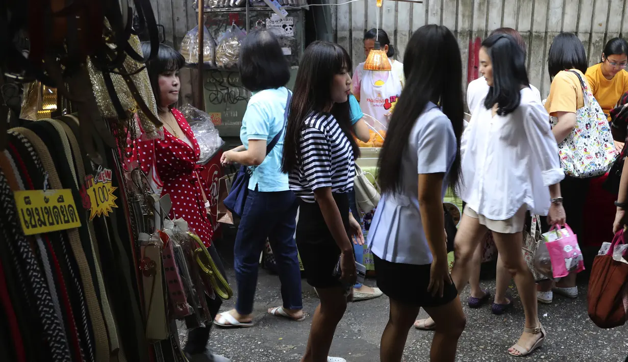 Sejumlah karyawan perempuan bekerja melewati lorong, yang terkenal dengan pedagang kaki lima dan pakaian, saat mereka pergi bekerja di pusat kota Bangkok, Thailand (8/11/2019). (AP Photo/Aijaz Rahi)