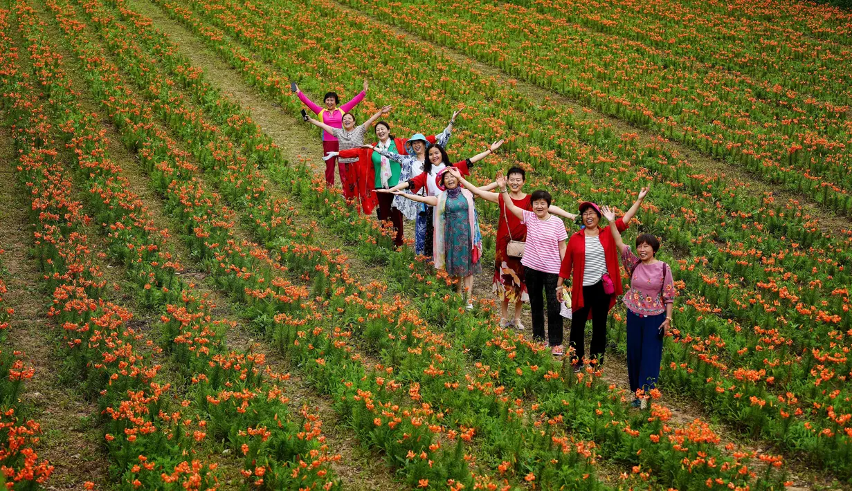 Orang-orang mengunjungi kebun bunga lili di Desa Baiyun, Wilayah Taibai, Provinsi Shaanxi, China barat laut (5/7/2020). Dalam beberapa tahun terakhir, dengan mempromosikan pariwisata pedesaan dan produk pertanian, desa ini telah mengangkat semua penduduknya keluar dari kemiskinan. (Xinhua/Liu Xiao)