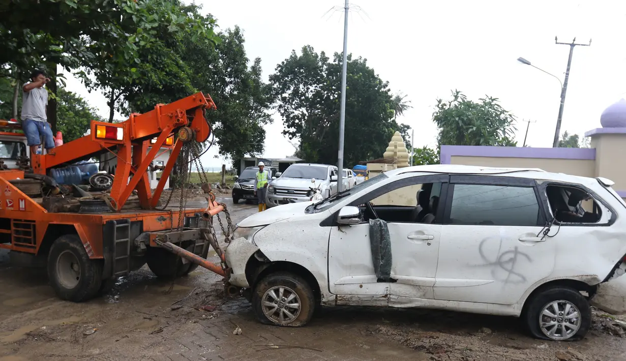 Petugas menderek mobil yang rusak akibat terjangan Tsunami Selat Sunda di Terminal Carita, Banten, Selasa (25/12). Terminal ini dijadikan tempat penampungan mobil yang hancur akibat tsunami. (Liputan6.com/Angga Yuniar)