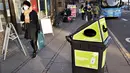 Seorang pejalan kaki berjalan melewati tempat sampah untuk masker sekali pakai, di Aarhus Center, Denmark, Senin (23/11/2020). Kota Aarhus menempatkan seratus tempat sampah khusu berukuran 240 liter yang dapat menampung sekitar 3000 masker bekas. (Henning Bagger/Ritzau Scanpix/AFP)