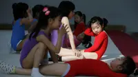 Sejumlah murid saling membantu saat berlatih senam lantai di sekolah atletik Shanghai Yangpu Youth Amateur, China (18/5). Latihan keras ini bisa membuat anak-anak menangis dan cedera ini diharapkan mampu menjadikan atlet berkualitas. (REUTERS/Aly Song)