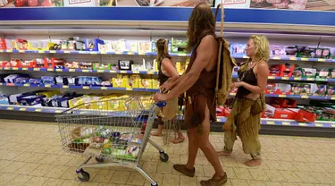 Liza, Werner dan Lucia mengenakan kostum primitif saat berbelanja di sebuah supermarket di Jerman, (28/7/14). (AFP PHOTO/DPA/CARSTEN REHDER)