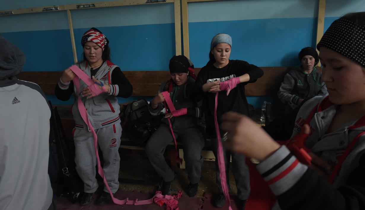 Para petinju wanita ini bersiap memakai sarung tinju saat berlatih di Stadion Ghazi, Kabul, Afganistan, (27/1/2016). (AFP/Shah Marai)