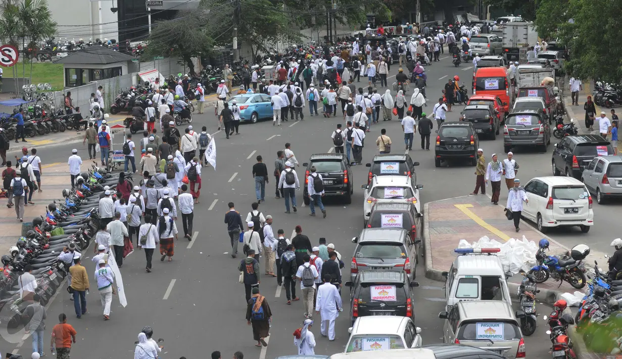Sejumlah kendaraan dan massa demo 2 Desember melintasi jalan kawasan Tanah Abang menuju Monas, Jakarta, Jumat (2/12). Mereka terlihat berbondong-bondong berjalan kaki untuk mengikuti demo 2 Desember di Lapangan Monas. (Liputan6.com/Helmi Afandi)