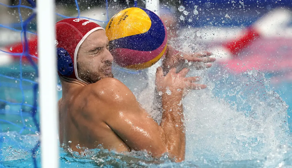 Penjaga gawang Yunani Emmanouil Zerdevas beusaha menghalau bola dalam pertandingan babak penyisihan polo air putra  Olimpiade Tokyo 2020 melawan Italia, Selasa (27/7/2021). (Foto: AP/Mark Humphrey)