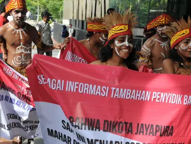 Sejumlah pemuda Papua mengenakan pakaian adat membawa spanduk berunjuk rasa di depan Gedung KPK, Jakarta, Senin (19/12). Mereka meminta KPK mengusut kasus korupsi pejabat yang mencalonkan diri pada Pilkada Jayapura 2017. (Liputan6.com/Helmi Affandi)