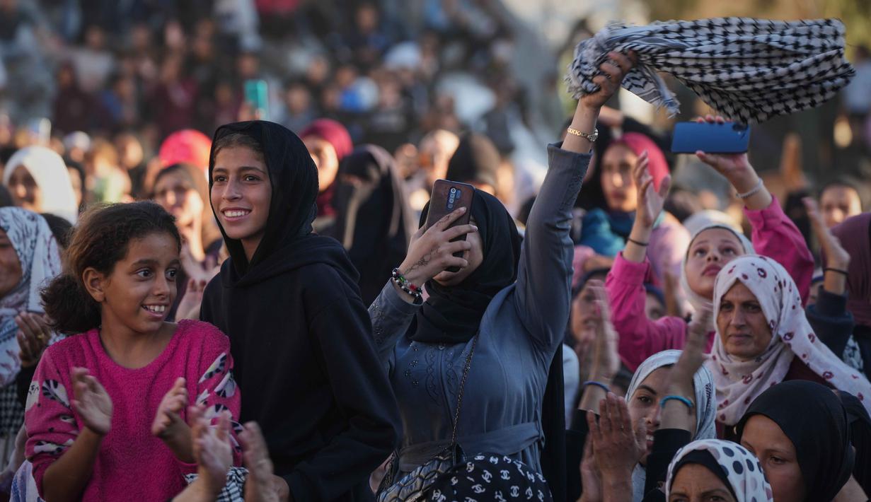 Acara yang dihadiri ratusan warga dan dimeriahkan dengan musik serta tarian tradisional itu menghidupkan kembali suasana yang selama ini dipenuhi kesedihan. Tampak dalam foto, warga Palestina menyaksikan dan merayakan upacara pernikahan massal di Kota Hamad, Khan Younis, Jalur Gaza, Selasa 2 Desember 2025. (AP Photo/Abdel Kareem Hana)