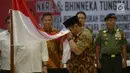 Anak pemimpin Darul Islam/Tentara Islam Indonesia (DI/TII) Sekarmaji Marijan Kartosuwiryo, Sarjono Kartosuwiryo mencium bendera Merah Putih saat pembacaan ikrar setia kepada Pancasila, UUD 45, NKRI dan Bhineka Tunggal Ika di Kemenko Polhukam, Jakarta, Selasa (13/8/2019). (merdeka.com/Imam Buhori)