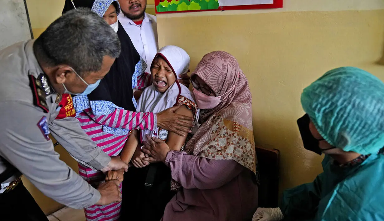 Orangtua, guru, dan polisi mencoba menenangkan seorang siswa saat akan disuntik pada kampanye vaksinasi COVID-19 di sebuah sekolah untuk anak-anak berkebutuhan khusus di Depok, Jawa Barat, Selasa (11/1/2022). Kampanye vaksinasi ini dilakukan oleh Polri. (AP Photo/Dita Alangkara)