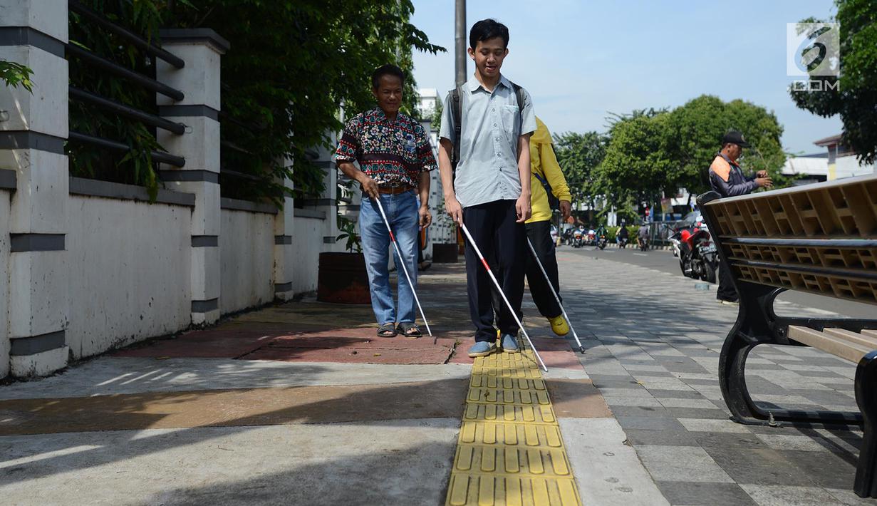 Penyandang disabilitas netra berjalan menyusuri ubin pemandu saat kampanye kegunaan ubin pemandu di trotoar Rawamangun, Jakarta, Selasa (2/4/2019). Kegiatan tersebut untuk memberikan pemahaman kepada masyarakat luas agar tidak terjadi penyalahgunaan di area ubin pemandu. (merdeka.com/Imam Buhori)